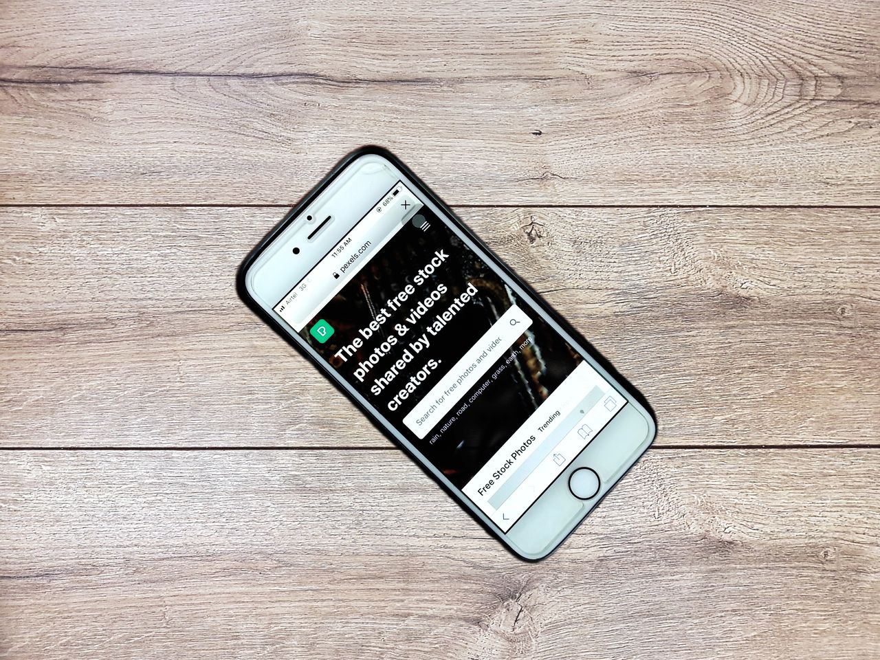मुखपृष्ठ Top view contemporary mobile phone with opened website on screen placed on wooden table